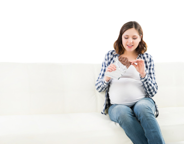 Young pregnant woman eating a chocolate - Foto, Bild