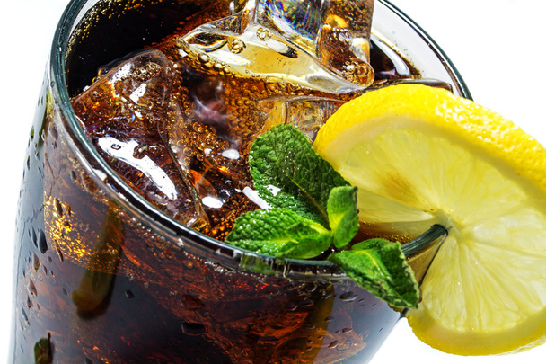 top of a glass of cola or coke with ice cubes, lemon slice and peppermint garnish, closeup - Fotó, kép