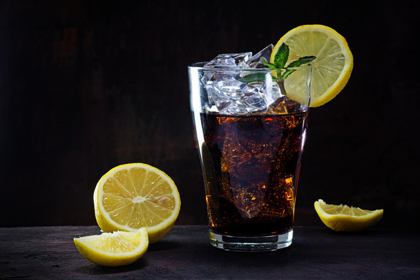 glass of cola or ice tea with lemon slices and peppermint garnis - Fotó, kép