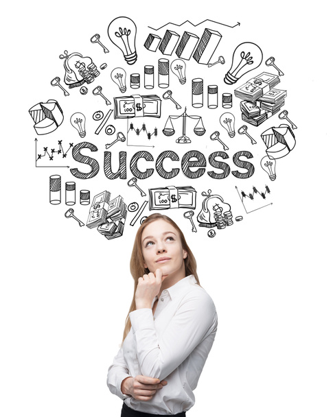 A young woman looking up and standing in front of a conrete wall with many different business icons and the word 'success' drawn on it. - Photo, image