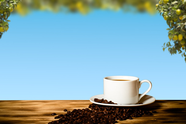 Café en grains et café en tasse blanche sur une table en bois en face d'une
  - Photo, image