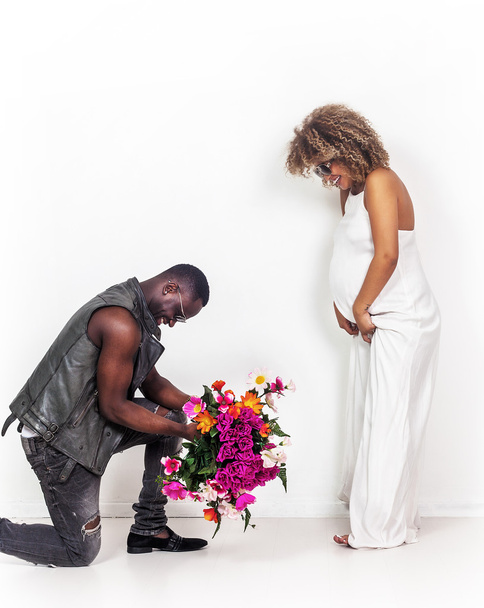 Handsome man portrait holding flowers near his pregnant girlfrie - Fotó, kép