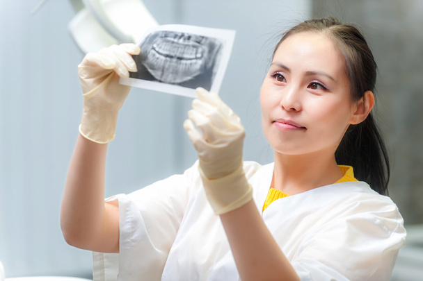 Стоматолог дивиться рентгенівське зображення
 - Фото, зображення