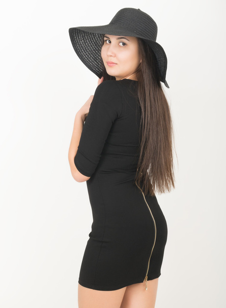 slender beautiful Asian girl in little black dress and a black wide-brimmed hat - Fotoğraf, Görsel