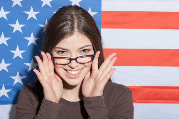 Cheerful intelligent woman near the usa flag - Фото, зображення