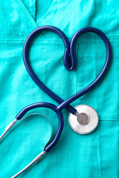 A stethoscope shaping a heart and a clipboard on a medical uniform, closeup - Φωτογραφία, εικόνα