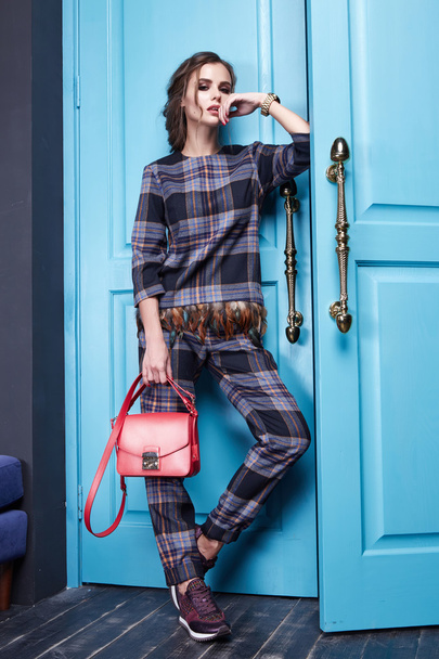 Beautiful sexy girl dressed style of fashion clothing new catalog of the collection, modern, stylish pants, fancy silk shirt accessory shoes with high heels, interior room with blue door entrance exit - 写真・画像