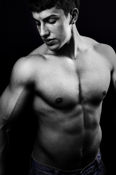 Muscular young man in the dark - Foto, afbeelding