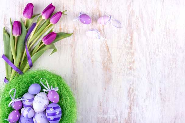 Paskalya yumurtaları ve Beyaz ahşap masa üzerinde çiçekler - Fotoğraf, Görsel