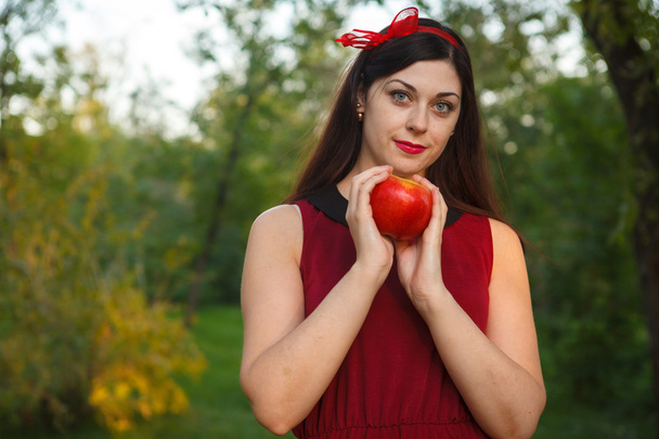 beautiful woman posing with an apple in the park - Photo, image