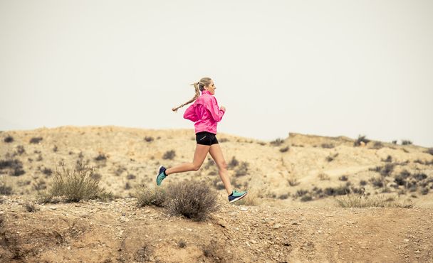 乾燥砂漠の風景の背景にハードにトレーニングと道路歩道汚れた道路走っている若いスポーツ女性 - 写真・画像