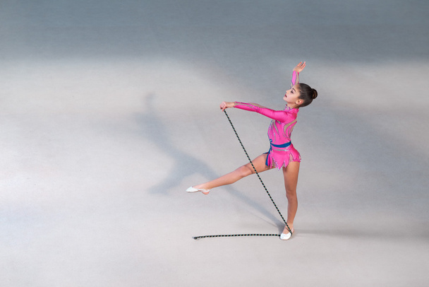 girl in dress doing exercise with gymnastic rope - Foto, Bild