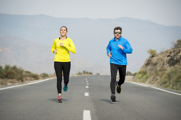 привлекательный спорт пара мужчина и женщина, бегущие вместе по асфальтированной дороге горный ландшафт
 - Фото, изображение