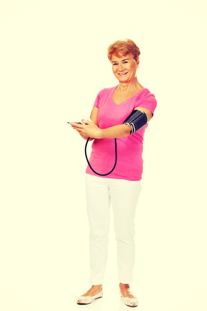 Smiling senior woman measuring blood pressure - Фото, изображение