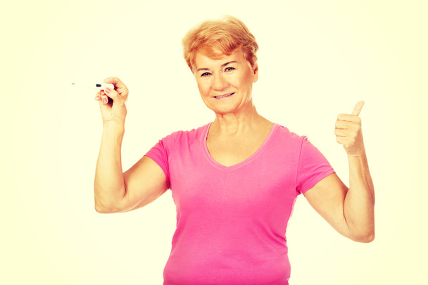 Senior woman shows thermometer and gesturing OK - Foto, Imagen