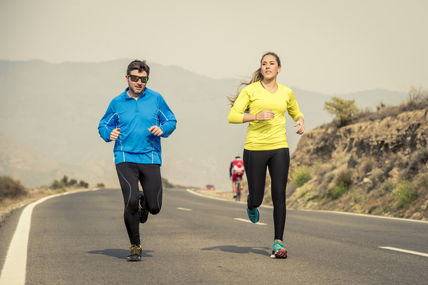 привлекательный спорт пара мужчина и женщина, бегущие вместе по асфальтированной дороге горный ландшафт
 - Фото, изображение