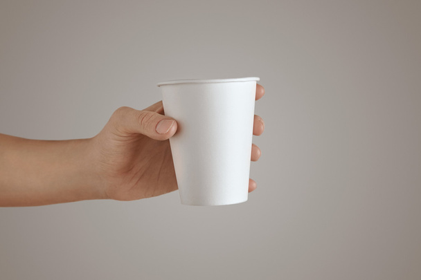 Woman hand holds paper glass isolated white - Foto, afbeelding