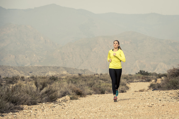 aantrekkelijke sport vrouw draait op aarde trail vuile wegnaar woestijn berg landschap-achtergrond - Foto, afbeelding