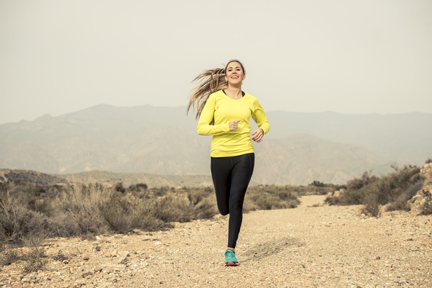 привлекательный спорт женщина бежит по земле тропа грязная дорога с пустынной горный ландшафт
 - Фото, изображение