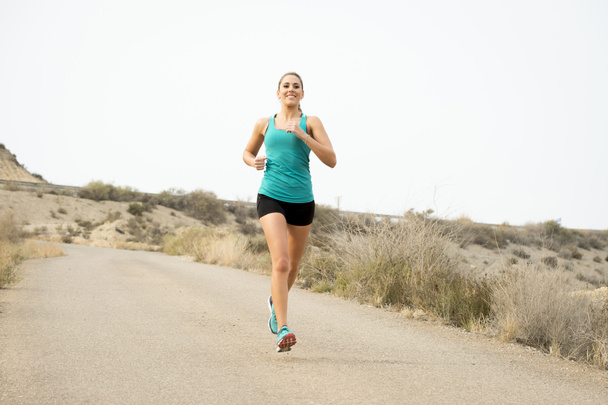 sportovní žena běží špinavý asfaltové silnici s tvrdě trénujete pozadí suché pouštní krajina - Fotografie, Obrázek