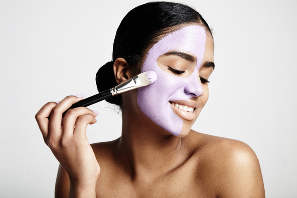 Vrouw aanbrengen van gezicht klei masker - Foto, afbeelding