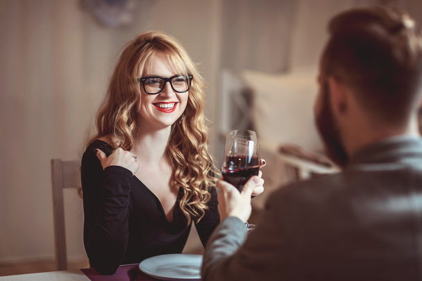 Beautiful young couple with glasses of red wine in luxury restaurant - Фото, зображення