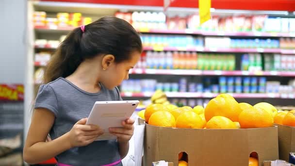 menina adolescente com tablet no supermercado para comprar laranja
 - Filmagem, Vídeo