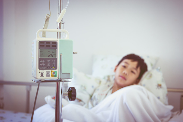 Ασιατικές αγόρι που βρίσκεται σε sickbed με έγχυση αντλία στάγδην ενδοφλέβια Iv - Φωτογραφία, εικόνα