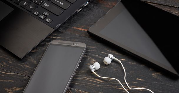 Laptop, Smartphone, Tablet-PC und Headset auf Holzgrund - Foto, Bild