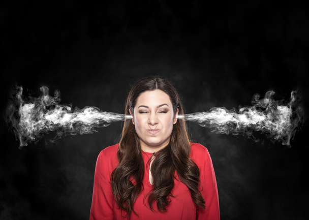 Rauch aus den Ohren einer Frau vor dunklem Hintergrund. - Foto, Bild