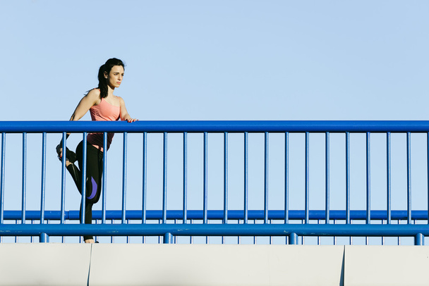 Young fitness woman runner stretching legs after run. - Fotoğraf, Görsel