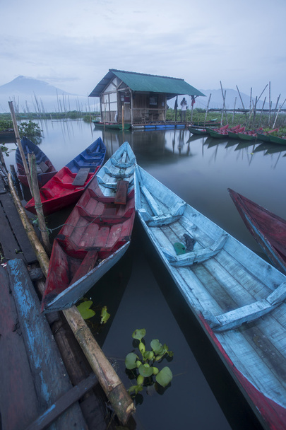 Vários barcos de pesca coloridos estacionados na costa do Lago Pening Rawa logo após o nascer do sol
. - Foto, Imagem