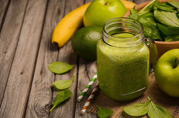 Green smoothie with apple, banana, avocado and spinach on a wooden rustic background. - Zdjęcie, obraz