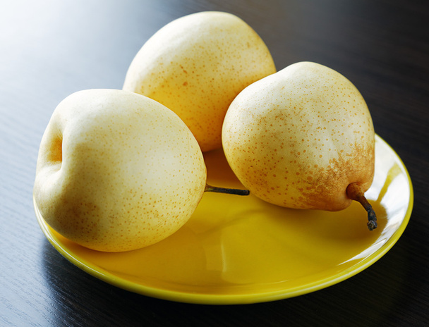 Three yellow pears on the plate on the table - Photo, image