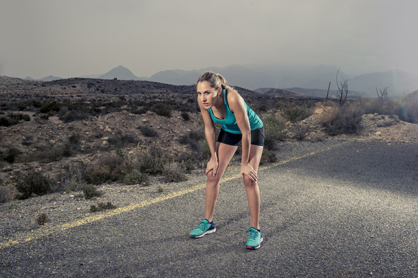 junge erschöpfte Sportlerin rennt auf Asphaltstraße und atmet - Foto, Bild