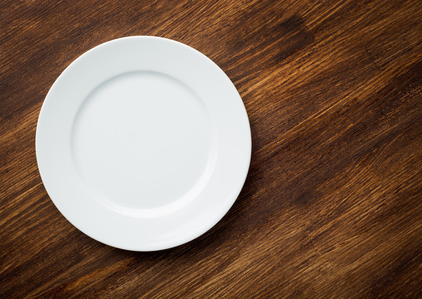 Empty white plate on wooden table - 写真・画像