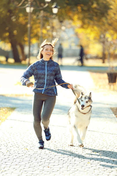 Woman jogging with her dog in park - Fotó, kép