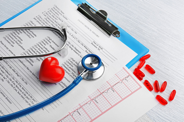 Stethoscope, pills, plastic heart on table - 写真・画像