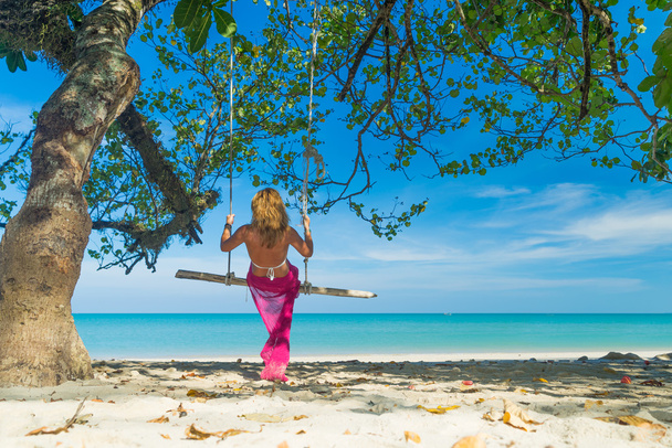 Woman in blue dress swinging at the beach - Foto, immagini
