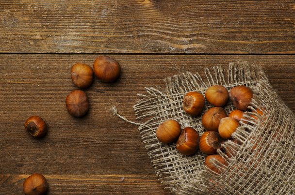 pile of hazelnuts in shell on wooden table  - Фото, изображение