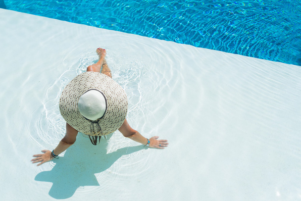 woman wearing a big hat relaxing at the swimming pool - Foto, Imagen
