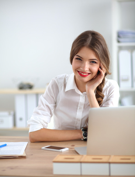Attractive businesswoman sitting  on desk in the office - 写真・画像