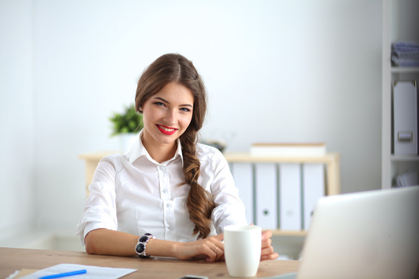 Attraktive Geschäftsfrau sitzt auf Schreibtisch im Büro - Foto, Bild