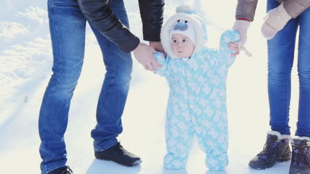 Una famiglia felice. Madre e padre insegnano a un bambino a camminare nel parco invernale
 - Filmati, video