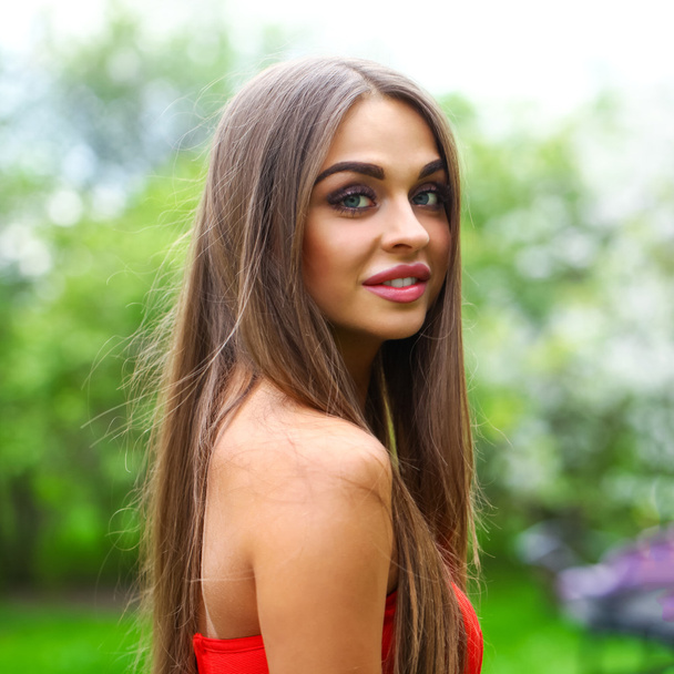 Happy young woman in red dress against the background spring flo - Fotografie, Obrázek