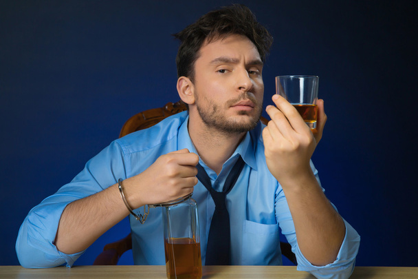 П'яний чоловік п'є алкоголь за столом
 - Фото, зображення