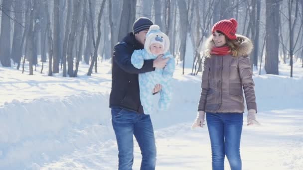 pai e mãe caminham no parque com a criança na lentidão do inverno
 - Filmagem, Vídeo