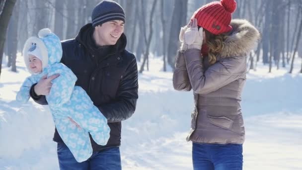 padre y madre caminan en el parque con el niño en la cámara lenta de invierno
 - Metraje, vídeo
