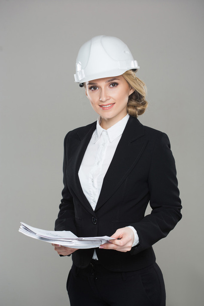 Woman architect with drawings. Beautiful girl in a building helmet - 写真・画像