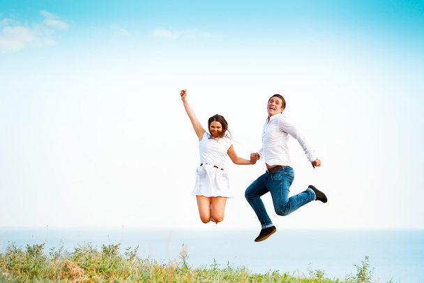 Молода щаслива пара стрибає на пляжі
  - Фото, зображення